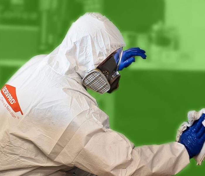 Person dressed in white SERVPRO PPE and blue gloves while cleaning.